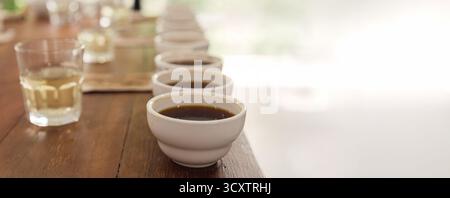 Row of coffee cups prepared for professional cupping session to evaluate aroma and flavor. Specialty coffee tasting setup in a cozy cafe or roastery e Stock Photo