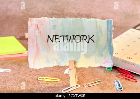 A creative workspace features a colorful sign displaying the word NETWORK. Surrounding it are vibrant sticky notes, paper clips, and a calculator, ins Stock Photo