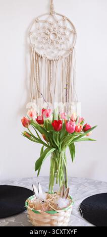 Colorful tulips in vase in soft boho style interior. Calm floral still life with delicate light, cozy atmosphere and natural aesthetic mood scene Stock Photo