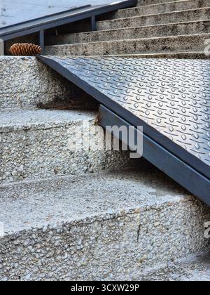 Concrete stairs with ramp in the park. Pine cone on the stairs. Modern steps and metal elements. Architectural textures concrete and metal. Stock Photo