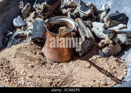 Traditional turkish coffee brewing on embers in a copper cezve with sand Stock Photo