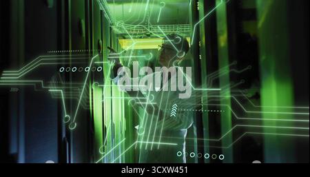 Pointing Korean man in white lab coat indicating rack panel in data center corridor, with holograms Stock Photo