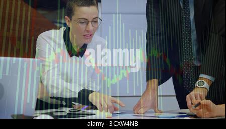 Colleagues reviewing charts at meeting table, with laptop showing financial graphs, copy space Stock Photo