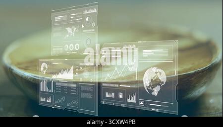 Translucent digital interface panels showing data charts and world map above wooden bowl in studio Stock Photo