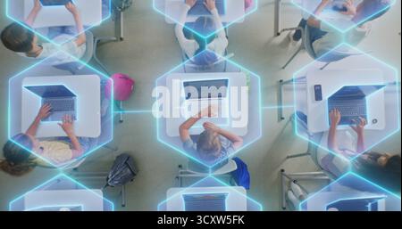 Children Sit at Desks Using Laptops, Surrounded by Luminous Digital Lines Symbolizing Virtual Connection and AI Collaboration. Technology Integration, and Future Focused Learning. Rotating Top View. Stock Photo