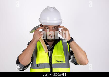 A man wearing a white hard hat and a high-visibility yellow vest  Stock Photo