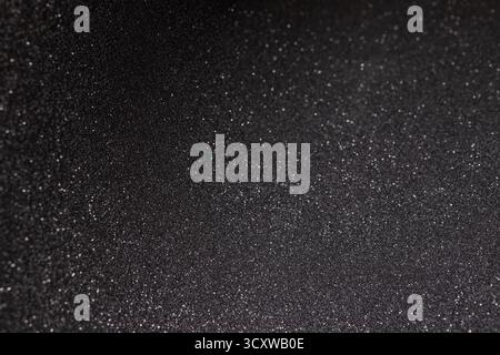 Black texture with micro relief curved along arc, surface detailed with subtle highlights and rare sparkles fading smoothly across abstract depth Stock Photo