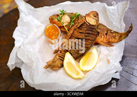 Fried whole fish with tomato and onion salad, on black background. High quality photo Stock Photo