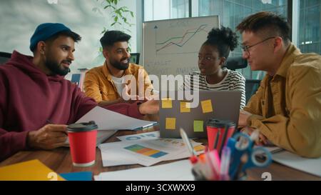 Focused concentrated informal casual startup business team considering paper document report information together talking solving finance problem Stock Photo