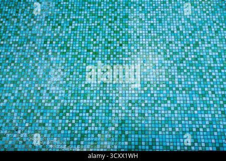 The floor of the pool is made of small square green and blue tiles with traces of ice on the surface, viewed from above Stock Photo