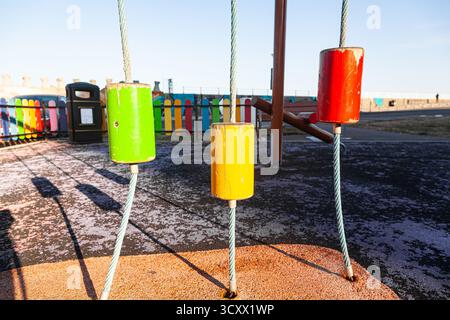 An empty children's playground with ropes tied to the ground with multi-colored wooden cylinders on it Stock Photo