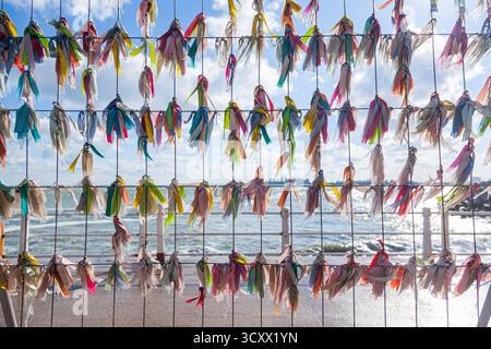 Multi-colored ribbons tied to a steel lattice overlooking the sea on a sunny day Stock Photo
