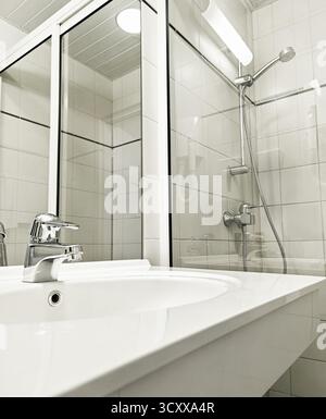 White Bathroom features a glass shower and modern sink, enhancing its contemporary aesthetic appeal Stock Photo