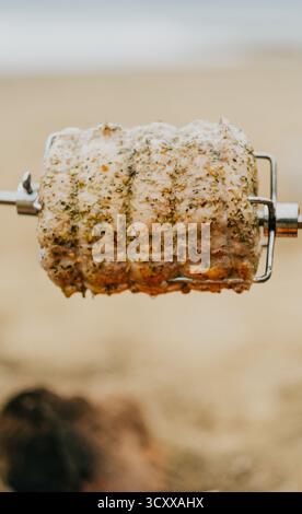 A piece of meat is being cooked on a spit. The meat is seasoned and has a nice aroma Stock Photo