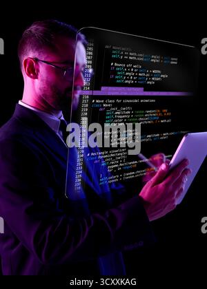 Modern collage. Developer studying holographic code reflected on transparent screen with tablet in neon light Stock Photo