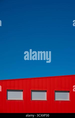 A graphic image of a red building set against the summer blue of a French sky Stock Photo
