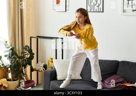 A girl in a yellow top and white pants enjoys playing at home. Stock Photo