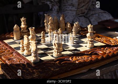 A beautiful antique wooden chess set with intricately carved pieces on a dark table during a game Stock Photo