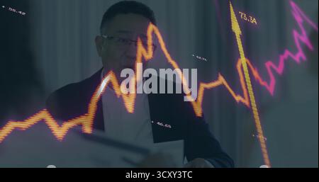 Analyzing market trends mature Chinese man in office, with translucent orange-magenta line charts Stock Photo