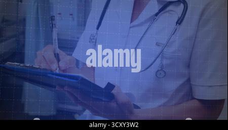Taking notes medical professional standing in clinic hallway, with blue clipboard and stethoscope Stock Photo