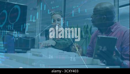 Two business professionals collaborating in conference room with documents and digital charts Stock Photo
