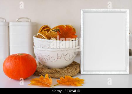 Bright pumpkins, dried oranges in bowl and blank cardboard on wooden table in cozy kitchen background, perfect for autumn, fall or Halloween and Thank Stock Photo