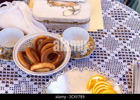 A charming outdoor still life with traditional turkish bagels, golden tea cups and a vintage wooden box on a lace tablecloth Stock Photo