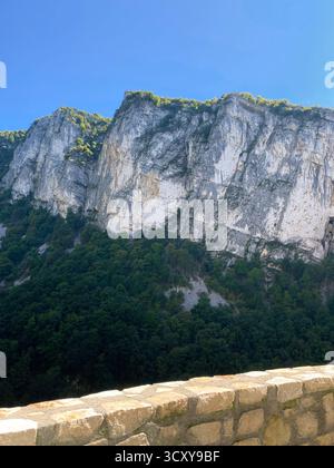 Steep Rocky Cliffs Above Forested Hillside Stock Photo