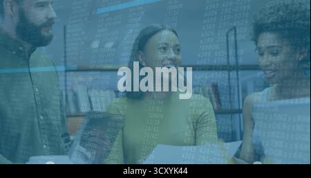 Three software developers reviewing code printout and laptop screen in office, with bookshelves Stock Photo