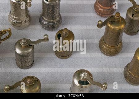 Collection of traditional metal coffee grinders with detailed engravings and patina finishes arranged on fabric, showcasing antique craftsmanship, rus Stock Photo
