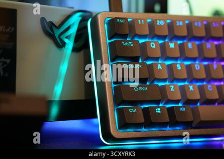 Colorful mechanical keyboard with RGB lighting next to an illuminated gaming monitor setup Stock Photo