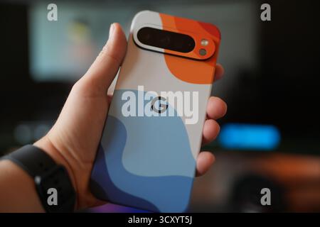 Colorful smartphone case held in hand with blurred background in indoor setting Stock Photo
