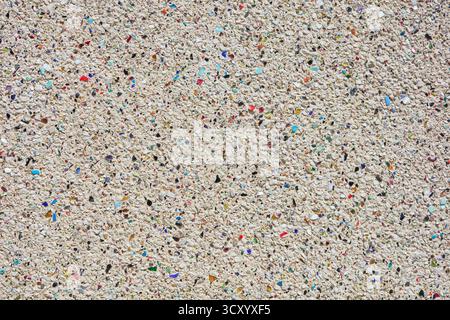 Bright, rough plaster with included grey and colored stones Stock Photo
