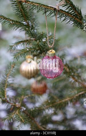 Small multi-colored glass balls on an outdoor Christmas tree close-up. Stock Photo