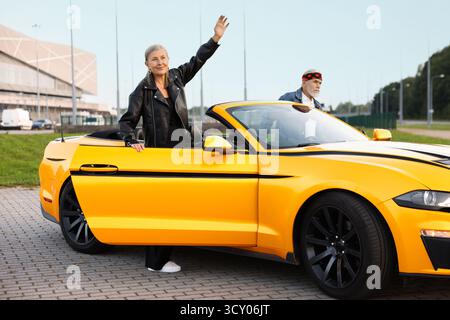 Stylish senior couple getting out of modern cabriolet outdoors Stock Photo