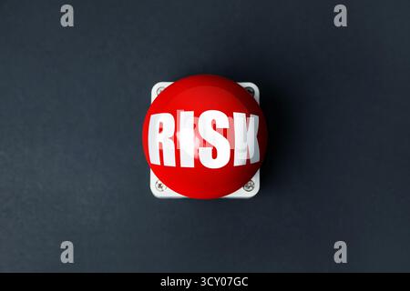 Red alarm button with word Risk on black background, top view Stock Photo