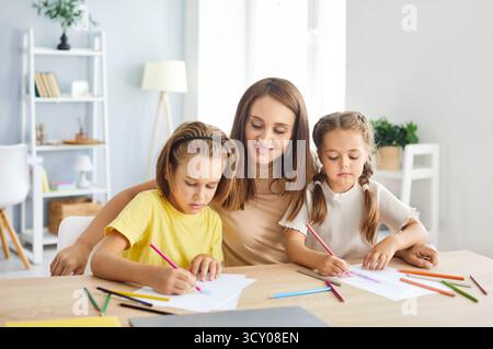 Mother And Children Spending Leisure Time Drawing Together At Home Stock Photo