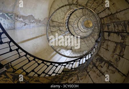 Looking vertically up a decrepit old wrought iron spiral staircase in the Phare de Calais, an prominent old lighthouse now monument Stock Photo