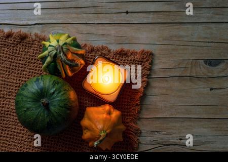 Decorative pumpkins and burning candle on wooden table, top view. Halloween holiday concept. Flat lay, copy space. Stock Photo