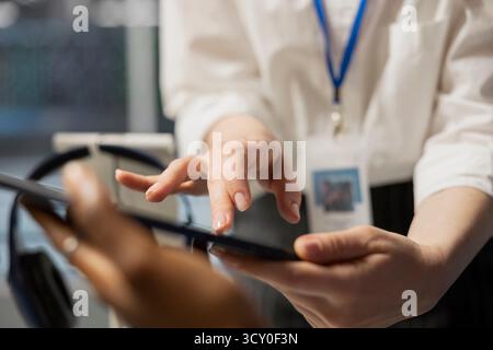 Close up of data center engineering team using tablet to inspect gear, doing maintenance tasks. Server farm coworkers using device to conduct system checks on network rigs Stock Photo
