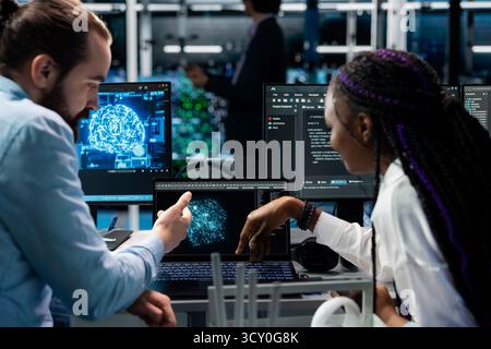 Computer scientists in data center installing upgraded server racks systems helped by AI technology. Server room IT experts upgrading enterprise networks hardware using artificial intelligence Stock Photo