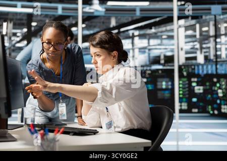 Data center manager supervising engineer implementing technology to improve resource allocation. Server hub supervisor overseeing employee doing predictive maintenance on equipment Stock Photo