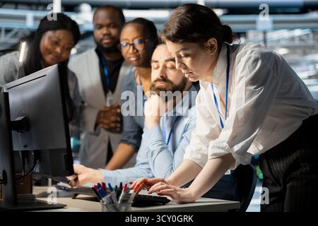Team of programmers in data center cooperating to update storage arrays software, configuring network virtualization. Server farm coworkers doing brainstorming, using computer to verify settings Stock Photo