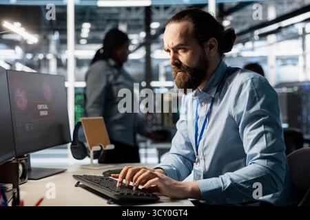 Frowning programmer in server room worried after reading diagnostic report showing critical hardware error on PC. Upset worker annoyed by system uptime issues warning notifications Stock Photo