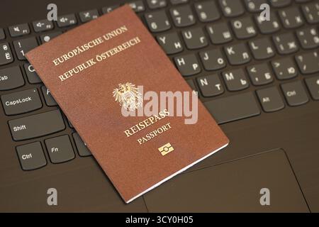Austria passport lies on black laptop keyboard buttons background close up. Technologies and control in Europe concept Stock Photo