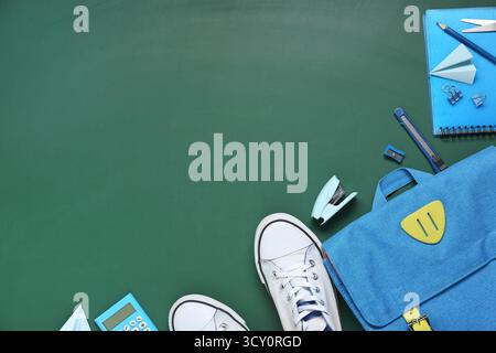 Different stationery with backpack and stylish sneakers on green background Stock Photo