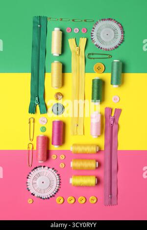 Composition with thread spools, zippers, ball pins and buttons on color background Stock Photo