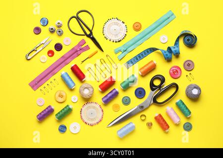 Composition with different thread spools and sewing accessories on yellow background Stock Photo
