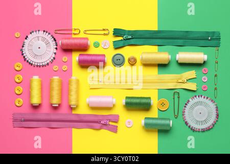 Composition with thread spools, zippers, ball pins and buttons on color background Stock Photo