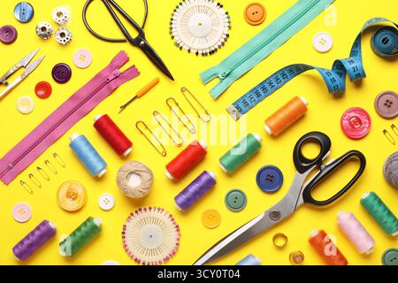 Composition with different thread spools and sewing accessories on yellow background Stock Photo